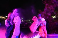 two people standing next to a car at night